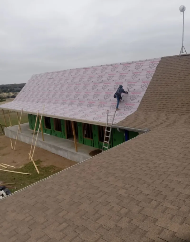 Worker preparing underlayment for a metal roof installation in Farmington